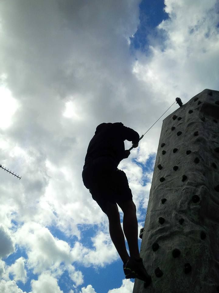 Silhouette of a climber on the wall against a bright cloudy sky, shot from below