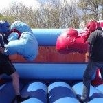 two boys geared up for a fight in a bouncy boxing inflatable with giant gloves and head guards